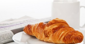 Image of Croissant coffee mug and newspaper on a desk